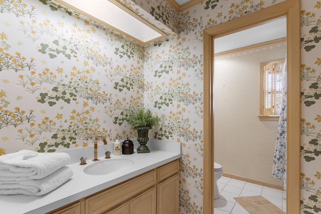 bathroom with toilet, vanity, tile patterned floors, and a skylight