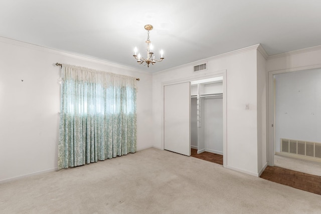 unfurnished bedroom with ornamental molding, carpet floors, a chandelier, and a closet