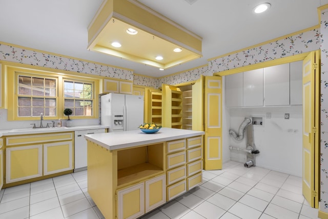 kitchen featuring sink, light tile patterned floors, a tray ceiling, a kitchen island, and white appliances