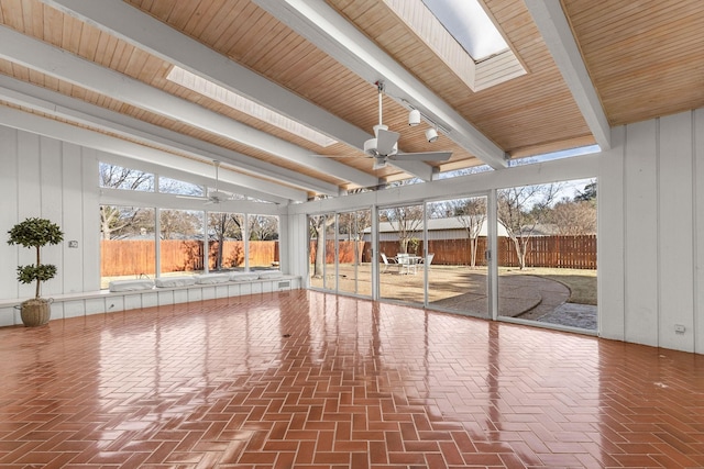 unfurnished sunroom with beamed ceiling, ceiling fan, a healthy amount of sunlight, and a skylight