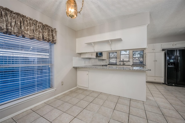 kitchen featuring pendant lighting, kitchen peninsula, black refrigerator with ice dispenser, and white cabinets