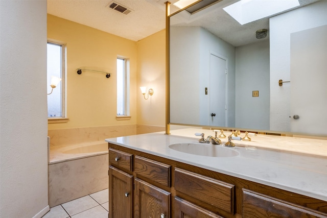 bathroom with tile patterned flooring, vanity, a skylight, and plenty of natural light