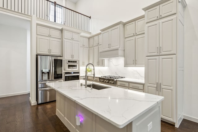 kitchen featuring light stone counters, appliances with stainless steel finishes, sink, and a center island with sink