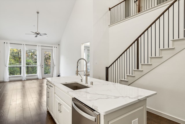 kitchen featuring dark wood-type flooring, sink, stainless steel dishwasher, an island with sink, and light stone countertops