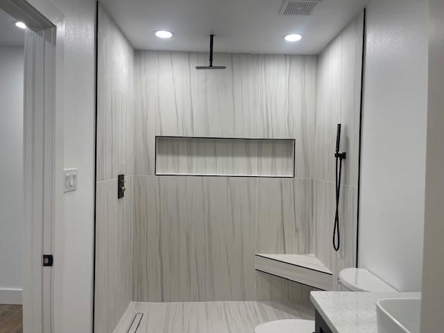 bathroom with walk in shower, vanity, and toilet