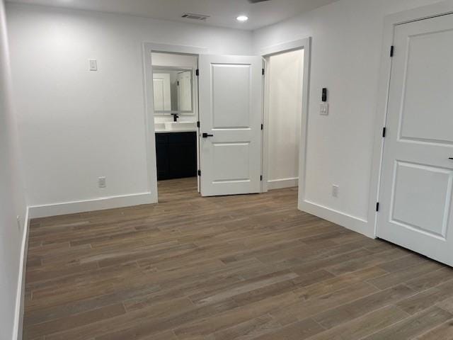 unfurnished bedroom with hardwood / wood-style flooring and connected bathroom