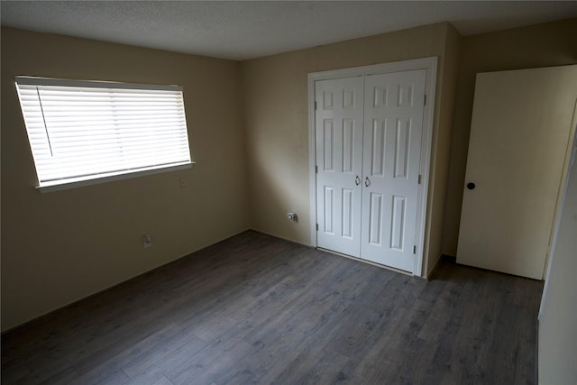 unfurnished bedroom with a closet, dark hardwood / wood-style floors, and a textured ceiling