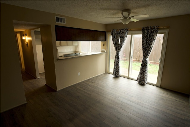 unfurnished living room featuring ceiling fan, dark wood-type flooring, and a textured ceiling