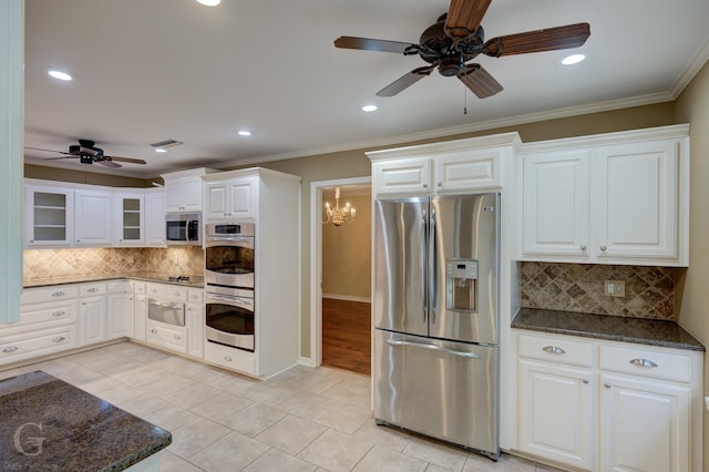 kitchen with white cabinetry, appliances with stainless steel finishes, dark stone countertops, and crown molding