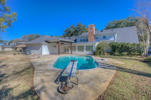 view of pool with a diving board, a patio, and a lawn