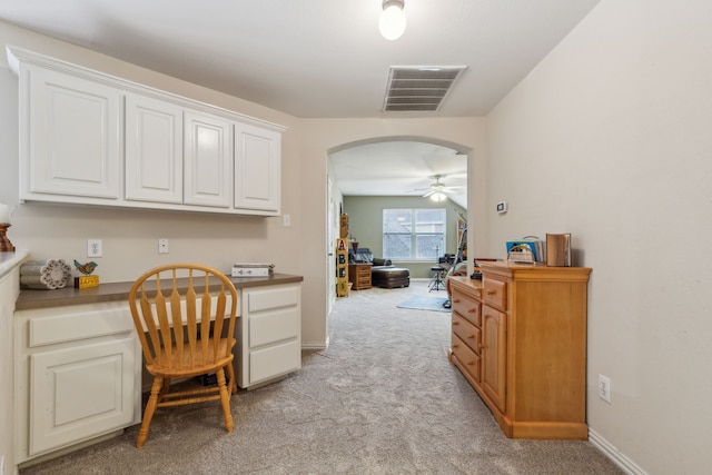 carpeted office space featuring built in desk and ceiling fan