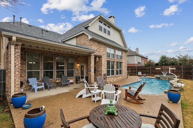 rear view of house featuring a fenced in pool and a patio