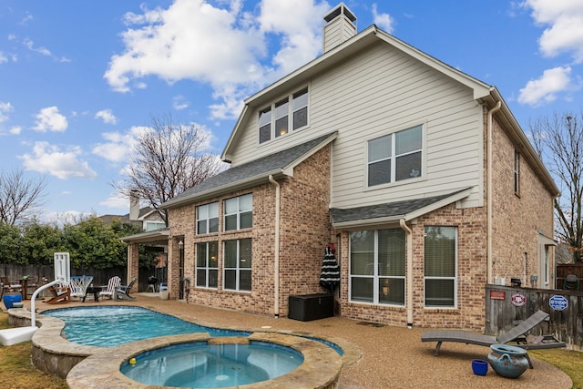 back of property with a pool with hot tub and a patio area