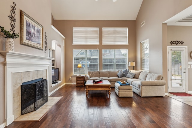 living room featuring a tiled fireplace, dark hardwood / wood-style floors, and high vaulted ceiling