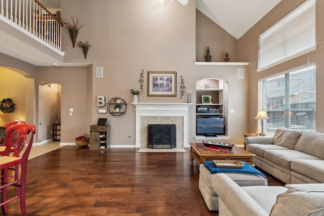 living room featuring hardwood / wood-style flooring, ceiling fan, a fireplace, and high vaulted ceiling