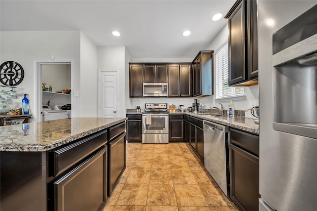 kitchen featuring sink, stone countertops, separate washer and dryer, dark brown cabinets, and appliances with stainless steel finishes