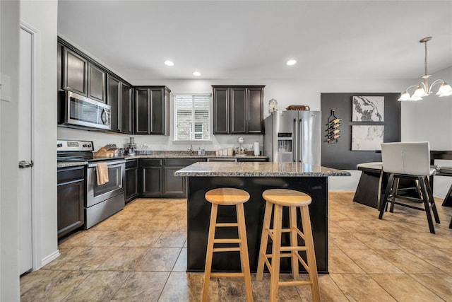 kitchen with appliances with stainless steel finishes, an inviting chandelier, a center island, a kitchen bar, and decorative light fixtures