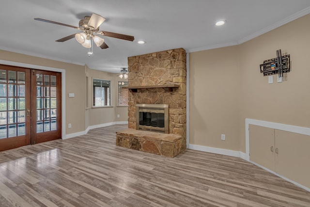 unfurnished living room featuring crown molding, a stone fireplace, light hardwood / wood-style floors, and ceiling fan