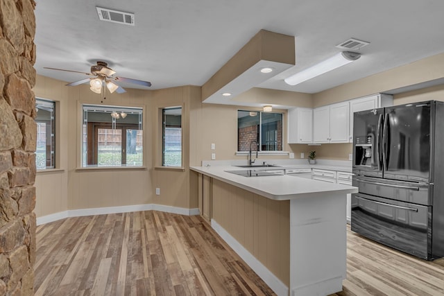 kitchen featuring kitchen peninsula, white cabinetry, ceiling fan, light hardwood / wood-style floors, and black fridge