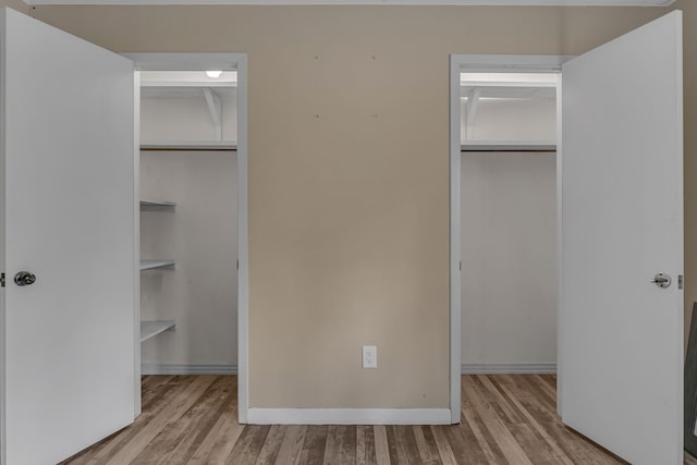 unfurnished bedroom with a closet, a spacious closet, and light hardwood / wood-style flooring