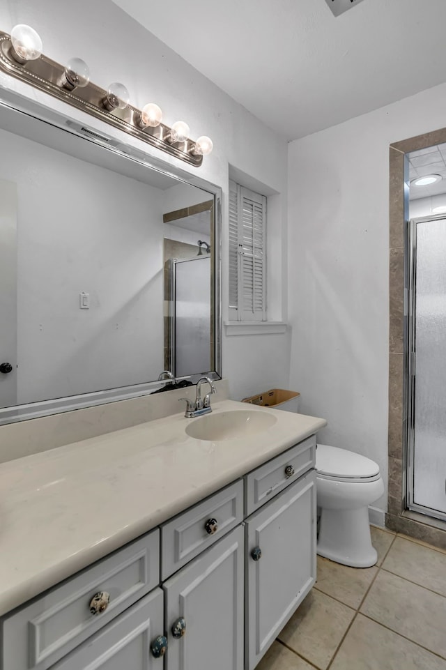 bathroom featuring walk in shower, vanity, toilet, and tile patterned flooring