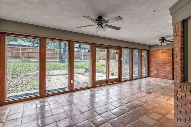 unfurnished sunroom with a healthy amount of sunlight and ceiling fan