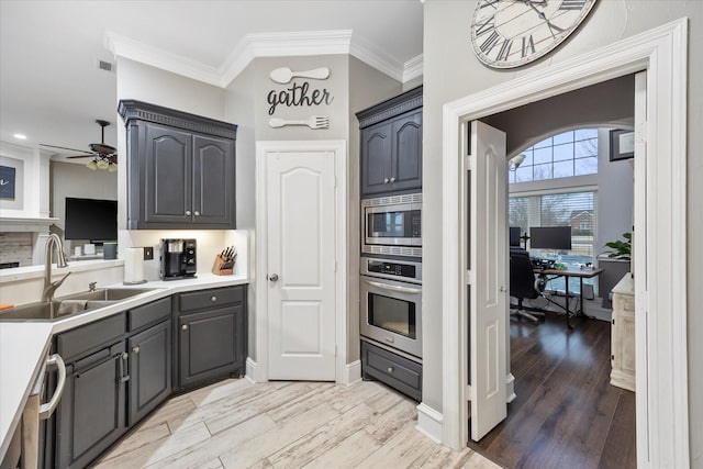 kitchen featuring sink, ornamental molding, ceiling fan, stainless steel appliances, and light hardwood / wood-style floors