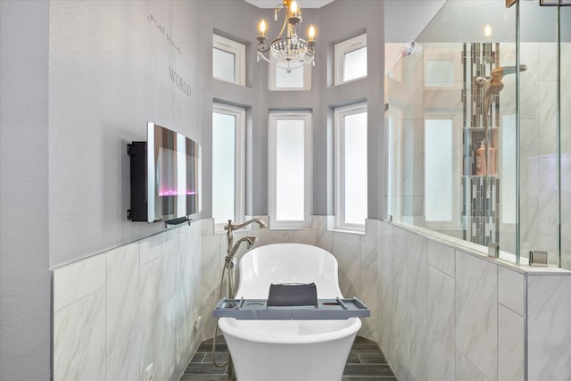 bathroom featuring tile walls, a notable chandelier, and independent shower and bath