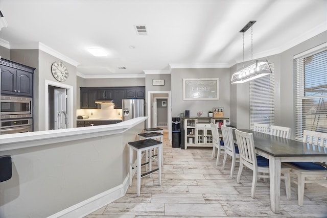 kitchen featuring ornamental molding, stainless steel appliances, sink, and hanging light fixtures