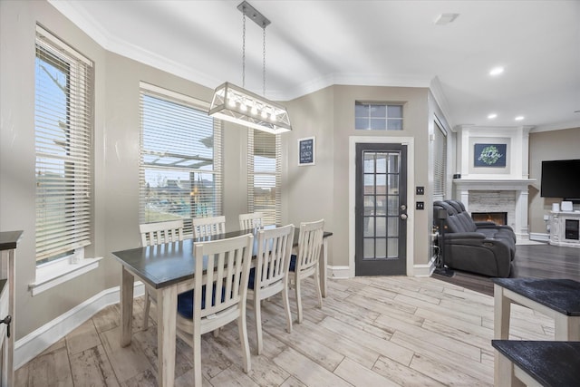 dining area featuring light hardwood / wood-style flooring, a fireplace, ornamental molding, and plenty of natural light