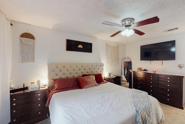 bedroom with ceiling fan, light carpet, and a textured ceiling