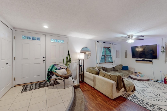 living room featuring ceiling fan, light hardwood / wood-style flooring, and a textured ceiling