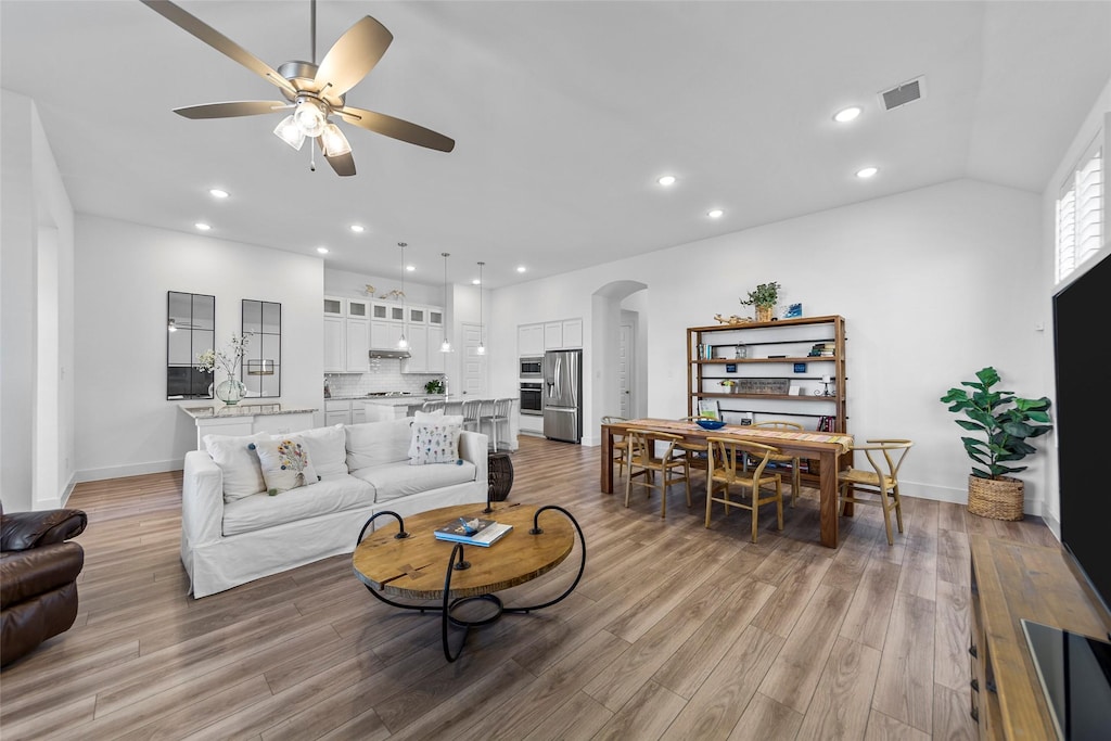 living room with lofted ceiling, light hardwood / wood-style floors, and ceiling fan