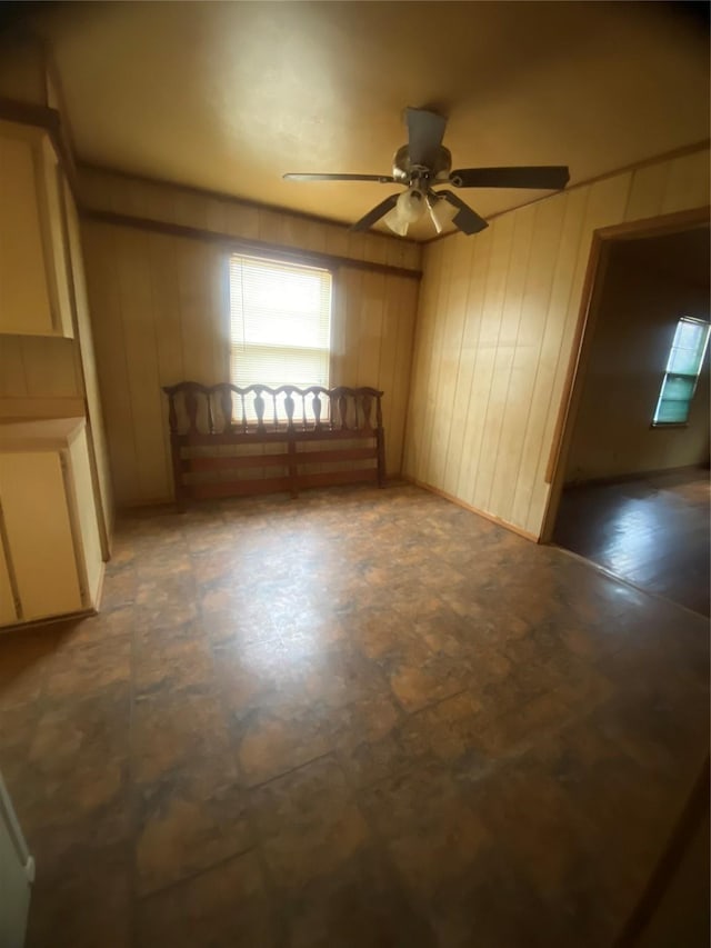 unfurnished room with ceiling fan and wood walls