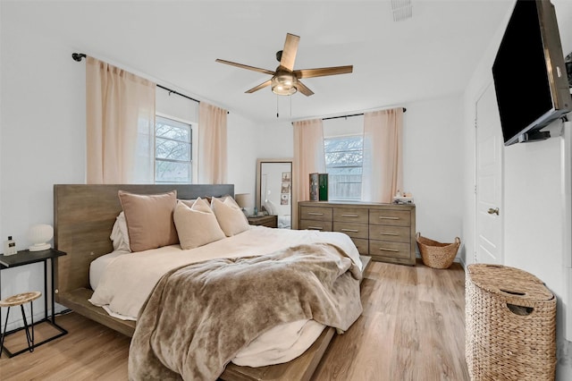 bedroom featuring multiple windows, ceiling fan, and light hardwood / wood-style flooring