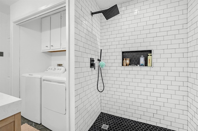 bathroom with vanity, independent washer and dryer, and tiled shower