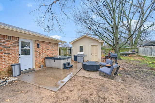 view of patio featuring a hot tub, grilling area, and a storage unit