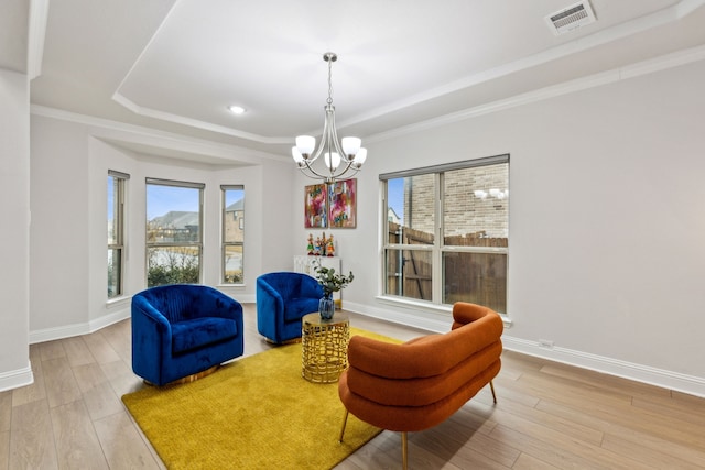 living area featuring a tray ceiling, a wealth of natural light, wood-type flooring, and a chandelier