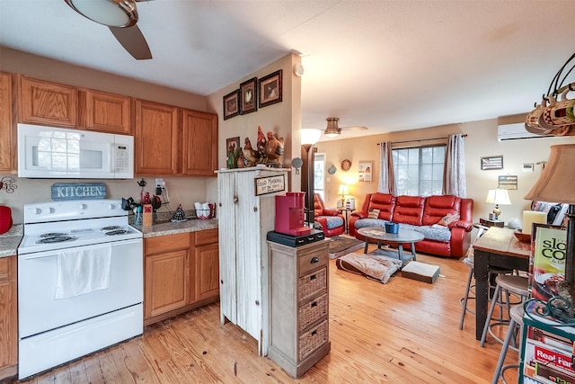 kitchen featuring ceiling fan, white appliances, a wall unit AC, and light wood-type flooring