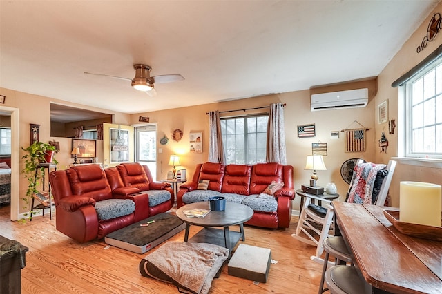 living room featuring a wall mounted AC, ceiling fan, and light hardwood / wood-style flooring