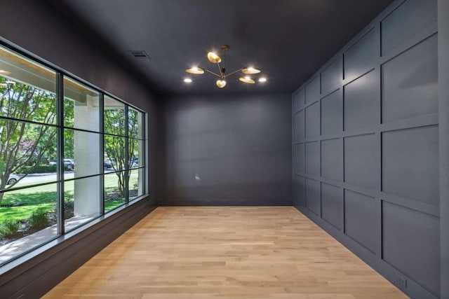 spare room featuring an inviting chandelier and light hardwood / wood-style floors