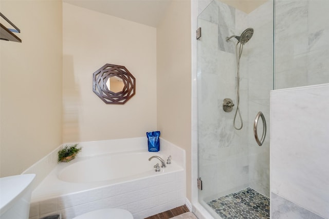 bathroom featuring shower with separate bathtub and toilet