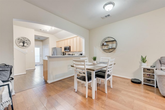 dining room with lofted ceiling and light wood-type flooring