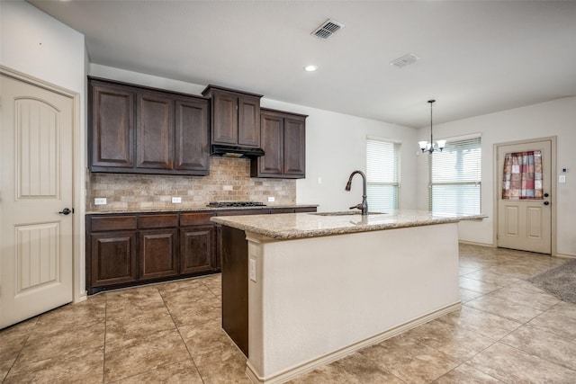 kitchen with dark brown cabinetry, sink, and a center island with sink