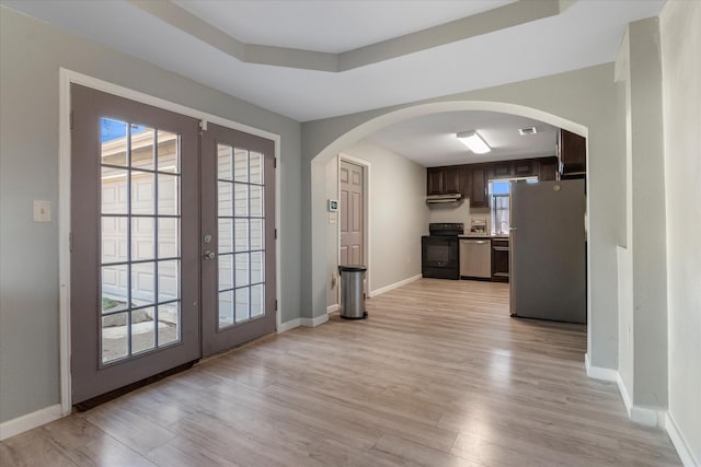 interior space featuring a raised ceiling, light hardwood / wood-style floors, and french doors