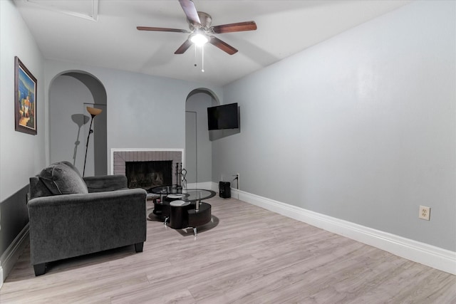 living room with light hardwood / wood-style flooring, a fireplace, and ceiling fan