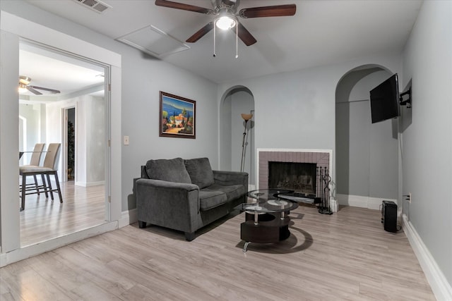 living room with a fireplace, light hardwood / wood-style flooring, and ceiling fan