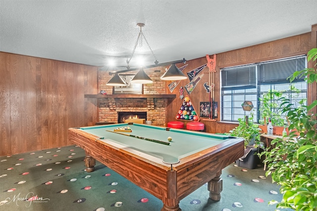 game room with a brick fireplace, carpet floors, a textured ceiling, and wood walls