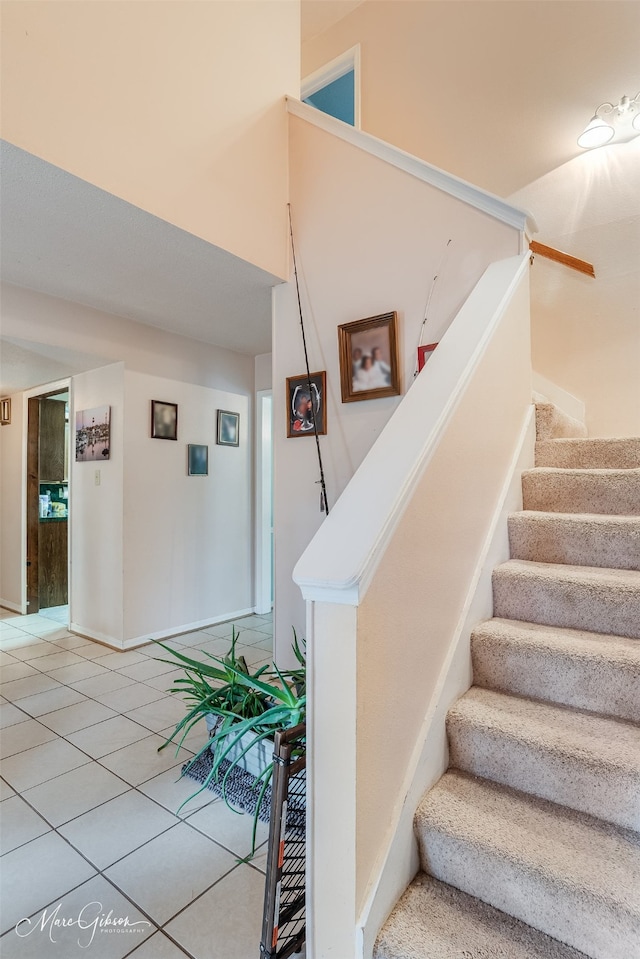 staircase featuring tile patterned flooring and a high ceiling