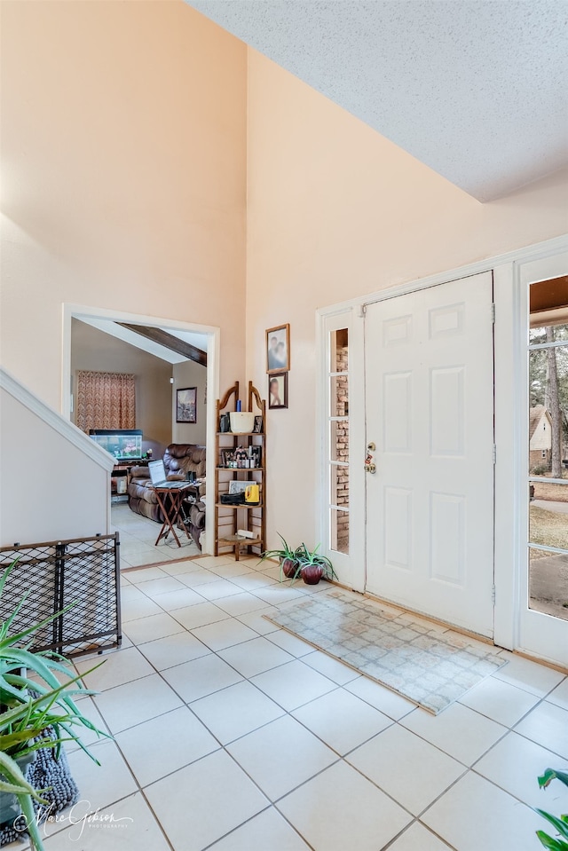 tiled foyer with high vaulted ceiling and a textured ceiling